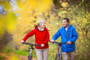 Active seniors having walk with bike in autumn nature. They having romantic time outdoor.